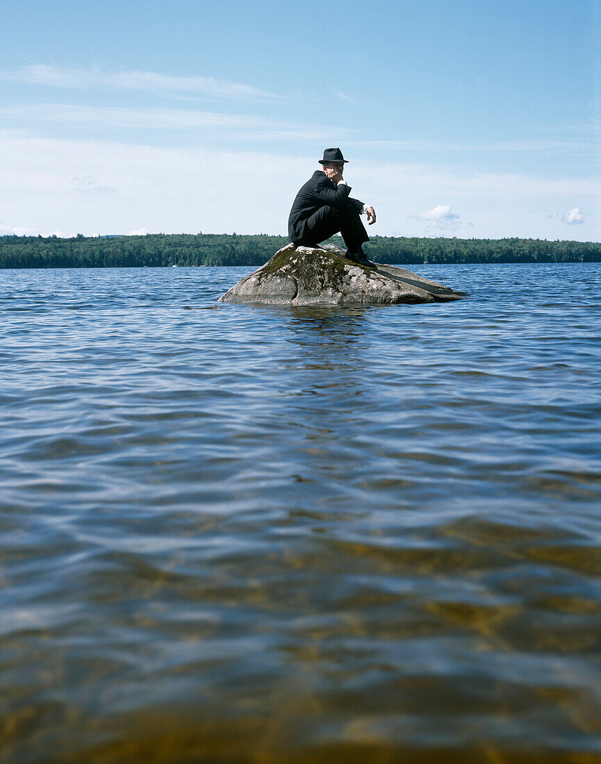 Man Sitting on Rock in Water