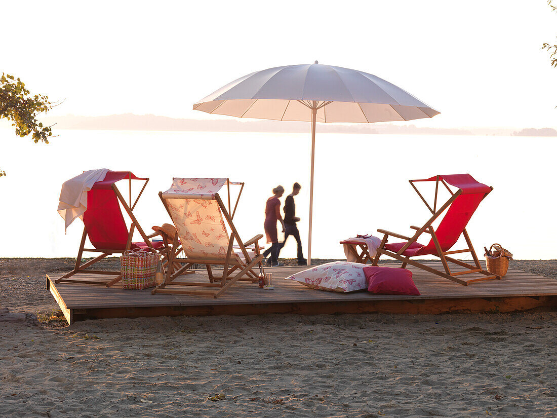 Three deckchairs and a sunshade at sunset, Feldwies beach, Chiemsee, Chiemgau, Bavaria, Germany