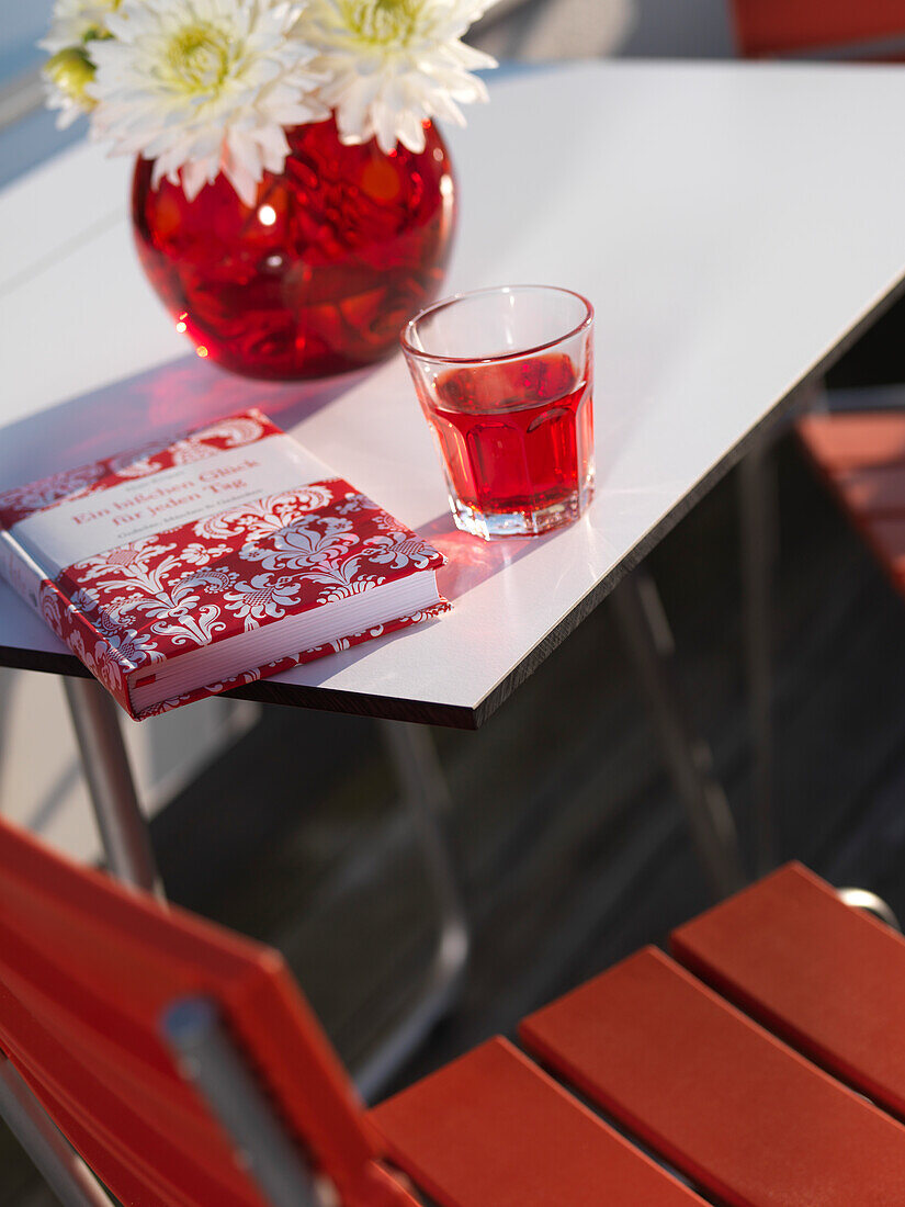 Modern decorated garden table with red book and red drink, Kolbermoor, Bavaria, Germany