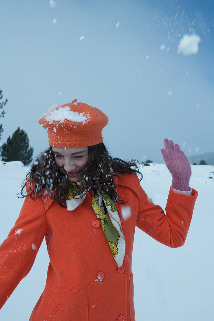 Teenage girl being hit with snowball, looking away, smiling