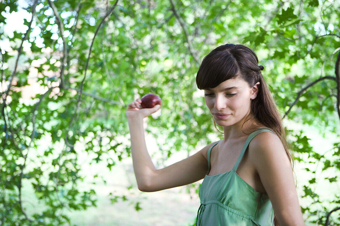 Junge Frau im Freien mit Apfel in der Hand, Blick nach unten, Nahaufnahme