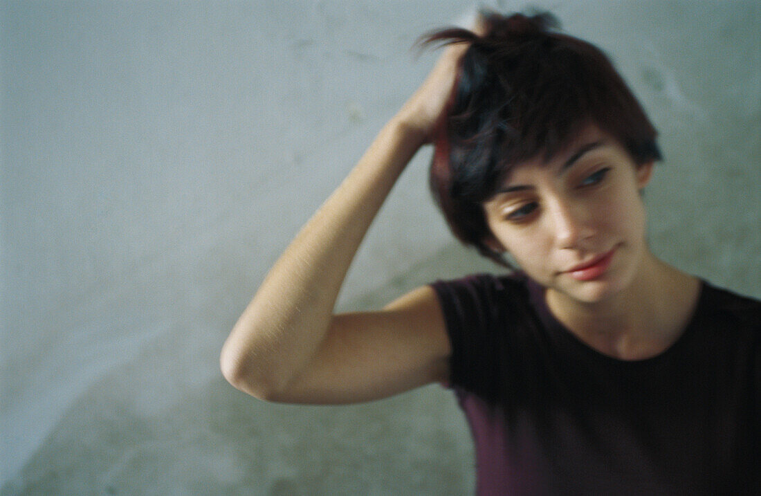 Young woman scratching head, looking away, blurred