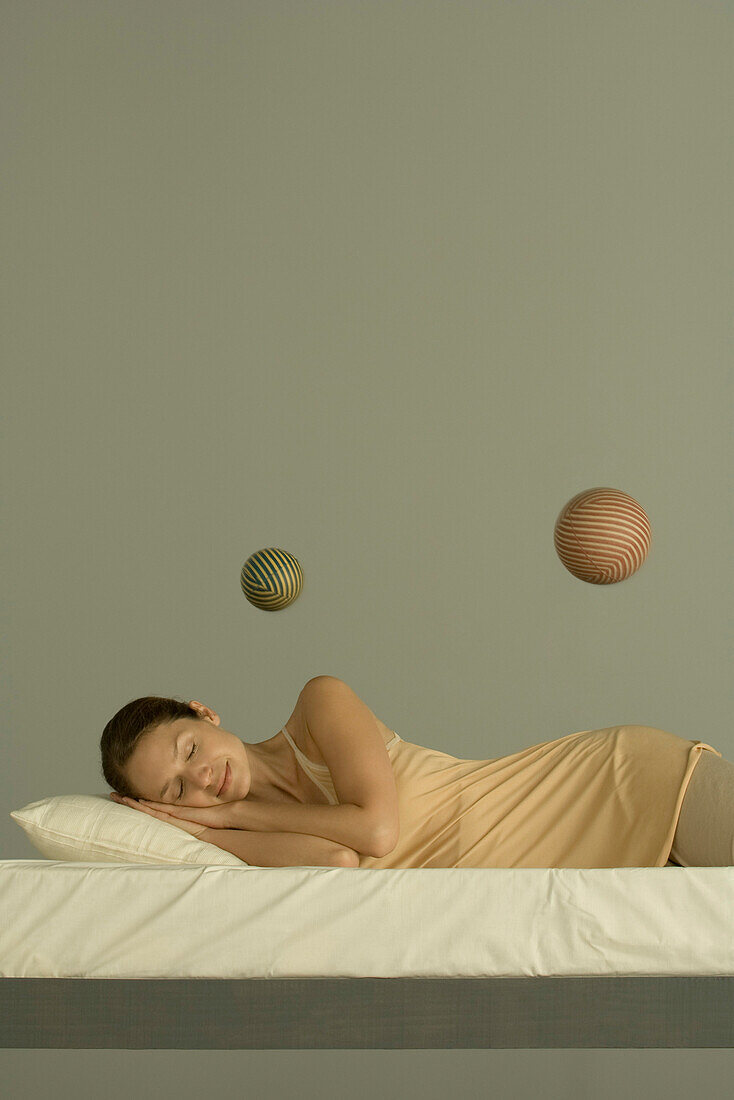 Woman sleeping in bed, two spheres floating in the air above her