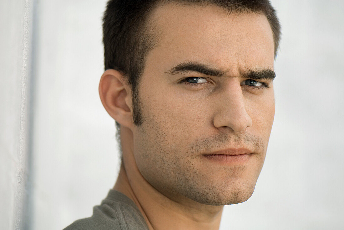 Man frowning at camera, raising one eyebrow