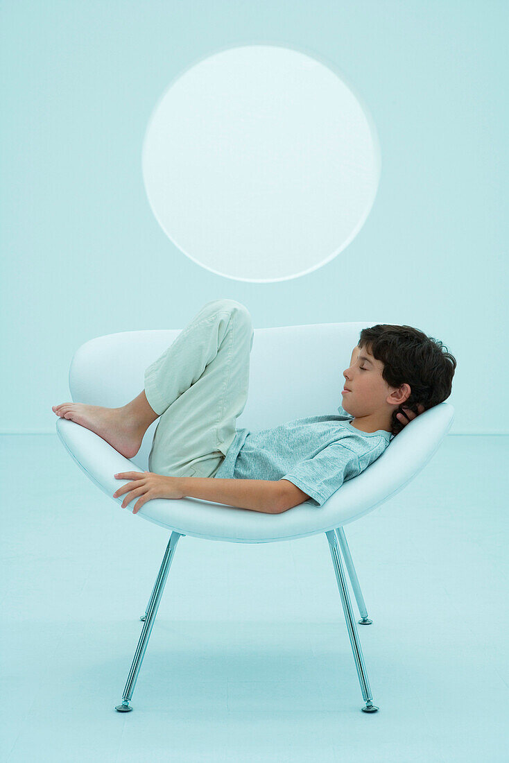 Boy reclining on chair, eyes closed