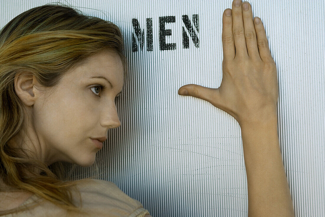 Woman resting head and hand against men's room door