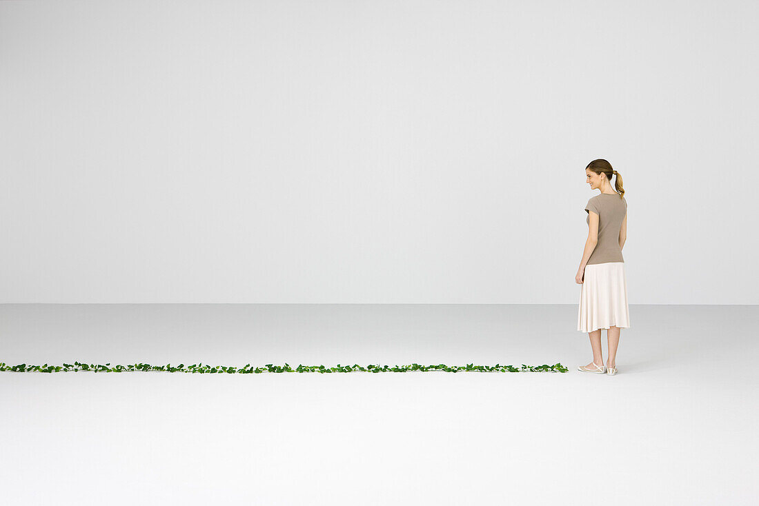 Woman standing, smiling down at vine growing on floor