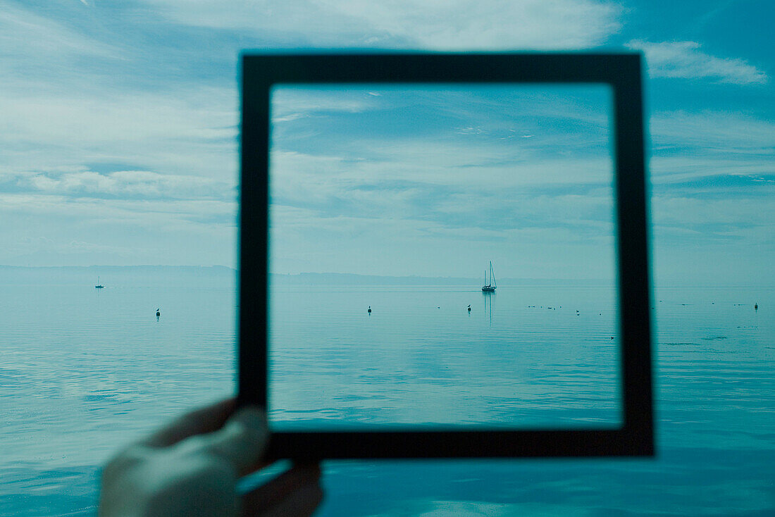 Person holding picture frame in front of seascape