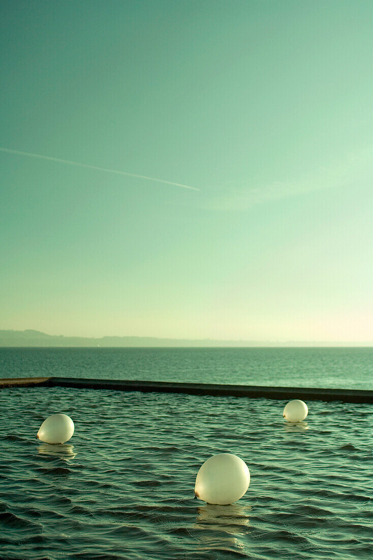 Balloons floating on lake, breakwater in background