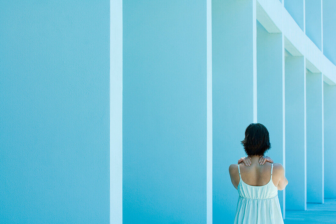 Woman massaging own shoulders, rear view