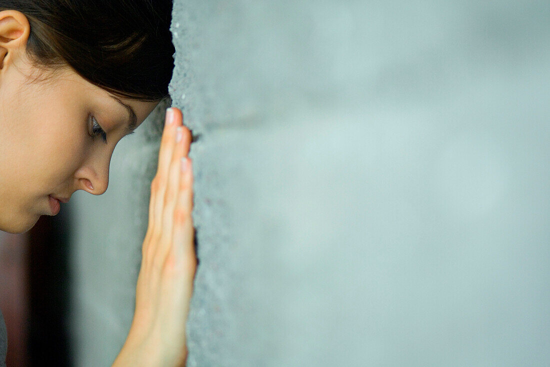 Woman leaning head against wall looking down