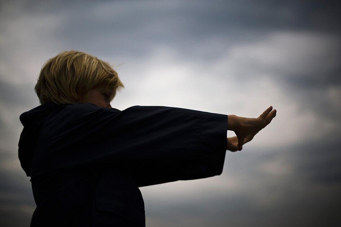 Boy with arms outstretched looking through finger frame