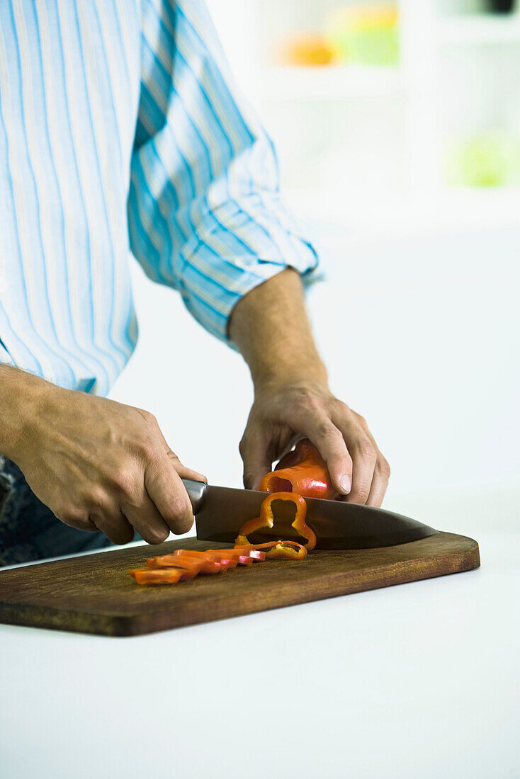 Slicing fresh red bell pepper on cutting board