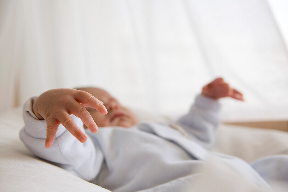 Baby sleeping in crib, focus on baby's hand