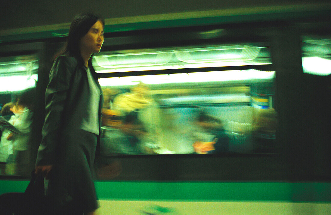 Woman walking on subway platform next to subway train, blurred