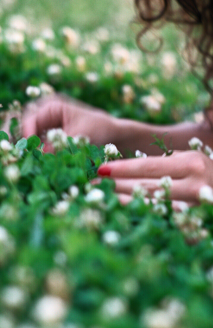 Frau liegt im Gras, Nahaufnahme der Hände