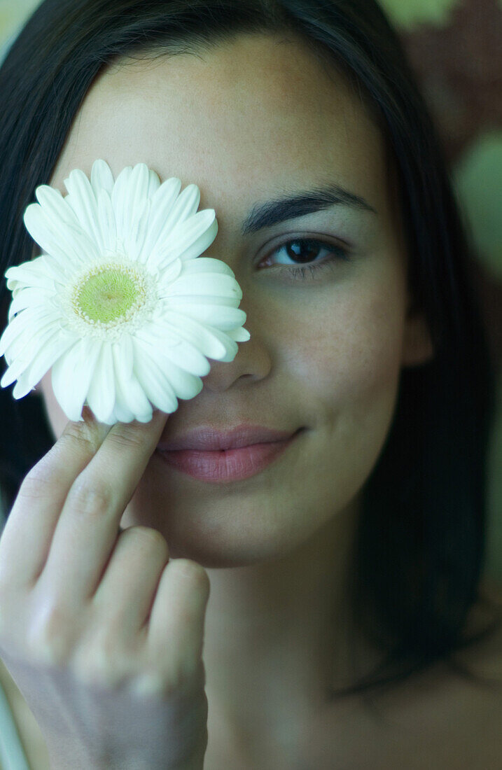 Frau hält sich Blume vor das Auge