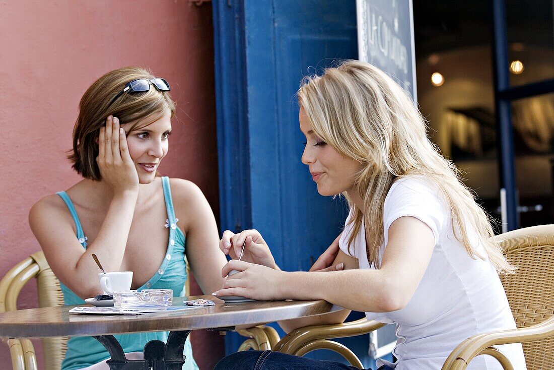 Two youg women discussing at coffee shop terrace