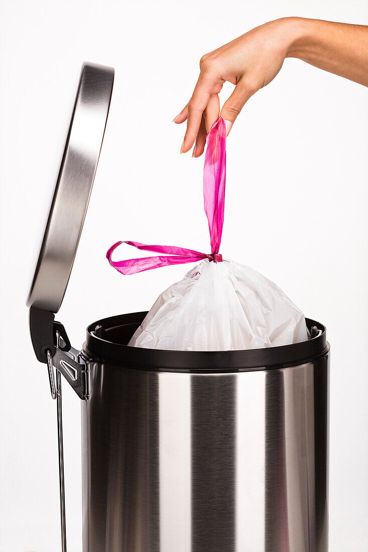 Woman's hand pulling a bag from the garbage