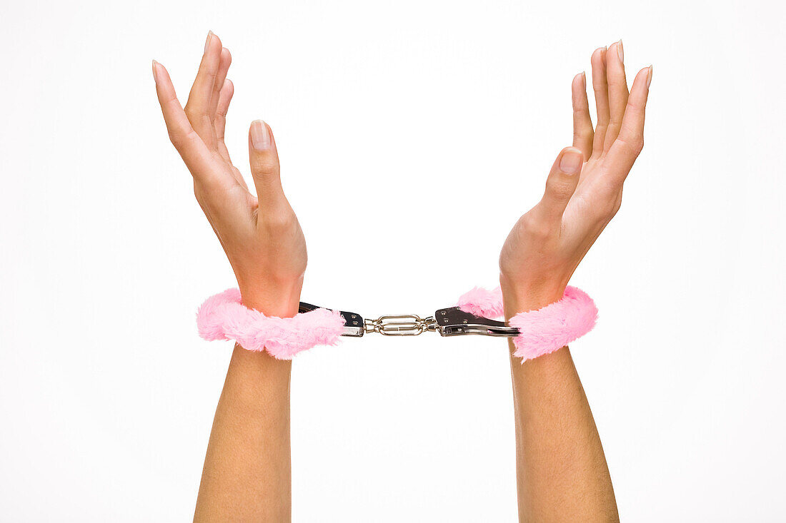 Woman's hands wearing fur handcuffs, close-up