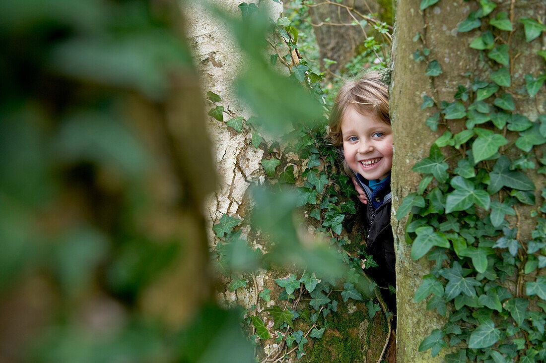 Smiling little girl behind a tree