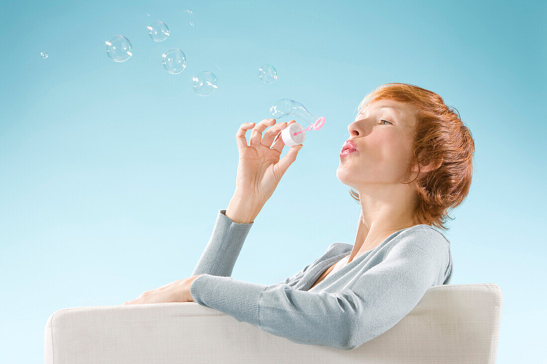 Claire portrait on light blue background, playing with bubbles