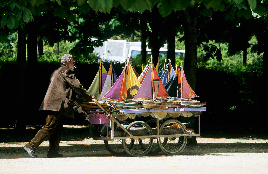 France, Paris, Tuileries garden, man pushing cart of model boats