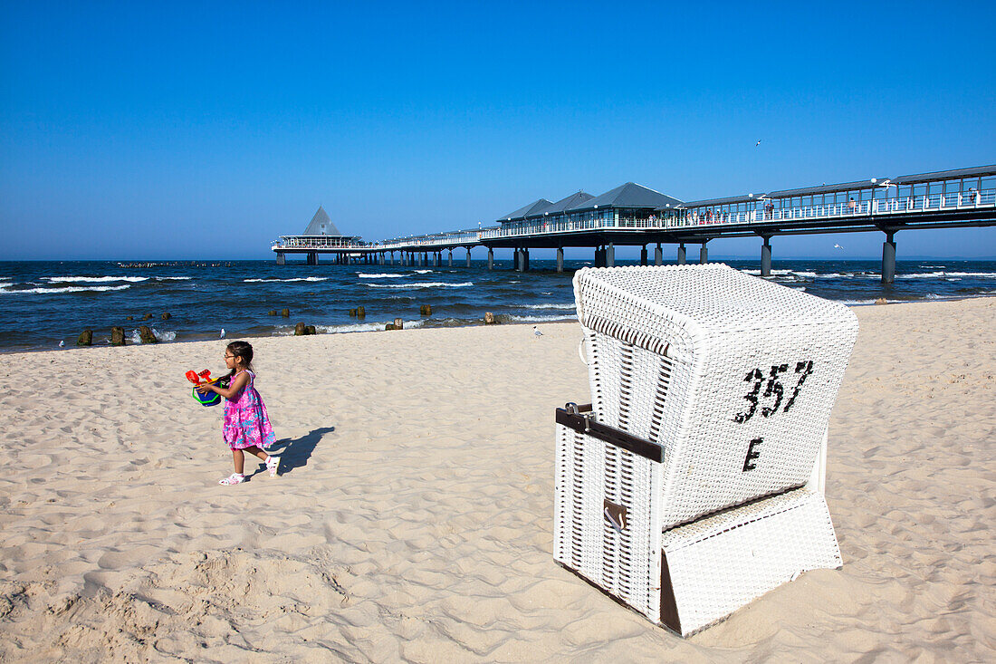 Little girl with beach toys, beach chair and pier, Heringsdorf, Usedom island, Baltic Sea, Mecklenburg-West Pomerania, Germany