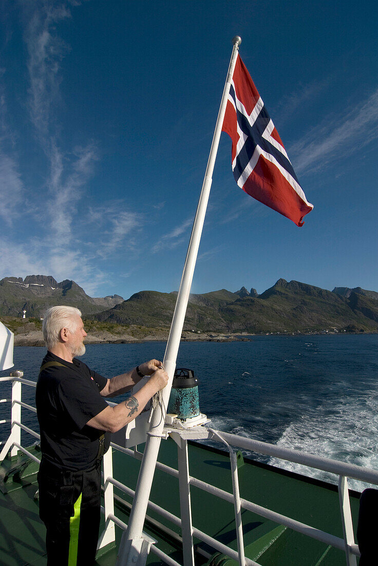 Norway, Lofoten Islands, sailor hoisting norwegian flag