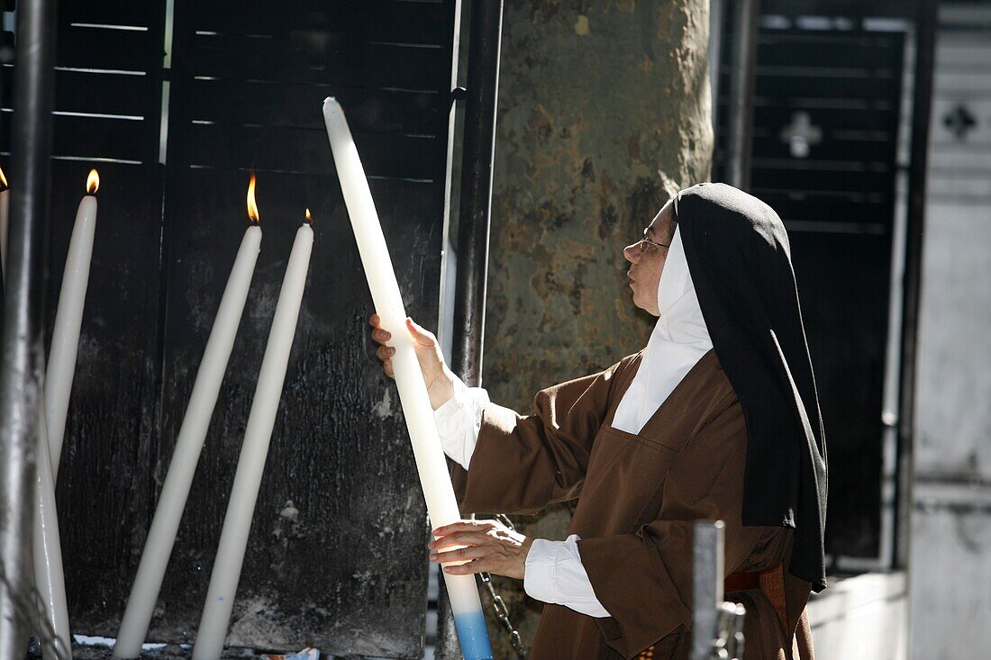 France, Lourdes, Nun lighting a candle at the Lourdes shrine