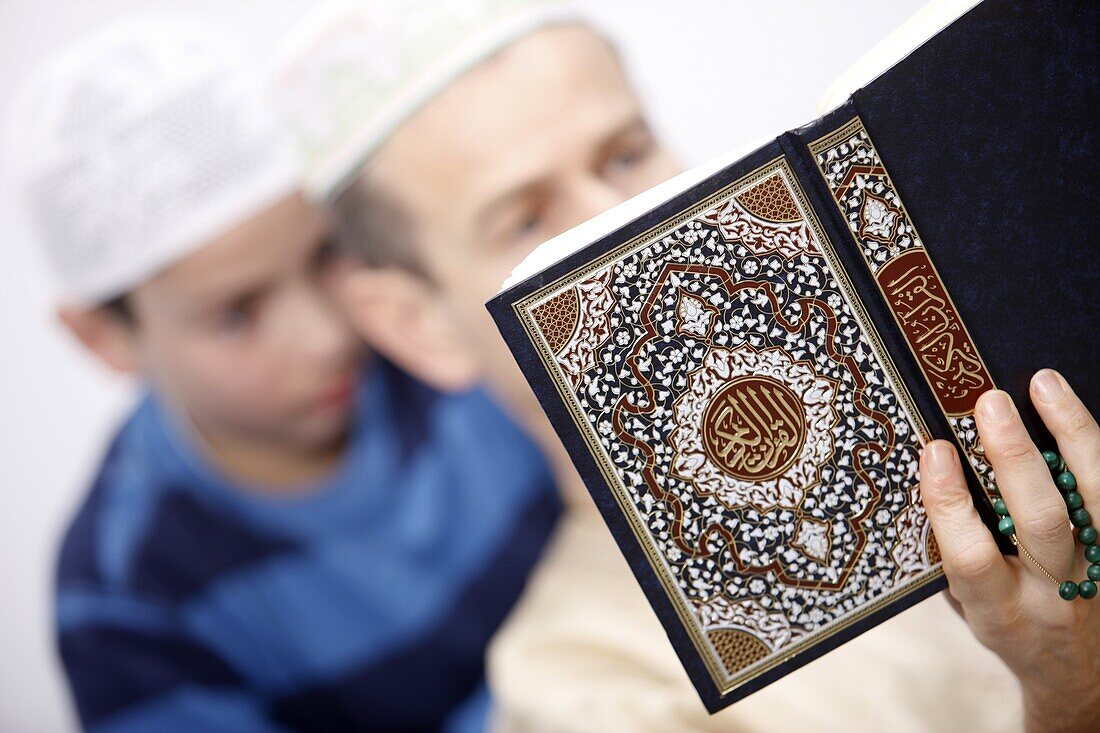 France, Paris, Man and boy reading Coran
