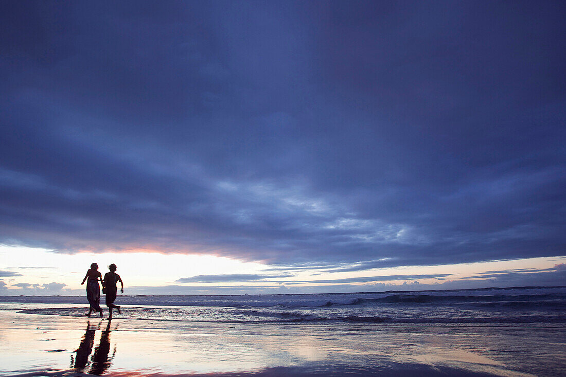 Couple walking along beach in twilight, Fuerteventura, Spain