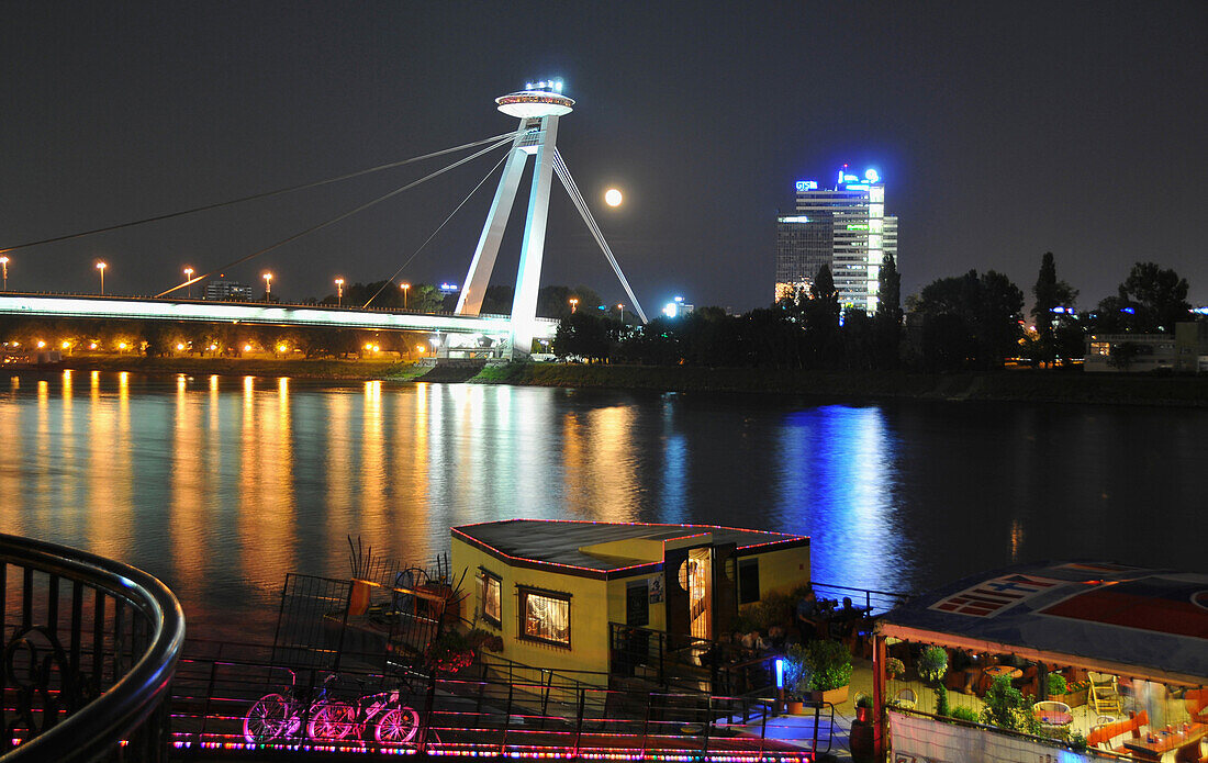 Ship at the bank of Danube river and Novy most bridge at night, Bratislava, Slovakia, Europe