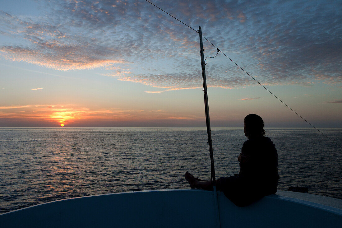 Tauchtouristin geniesst den Sonnenuntergang auf dem Tauchboot, Similan Inseln, Andamanensee, Thailand