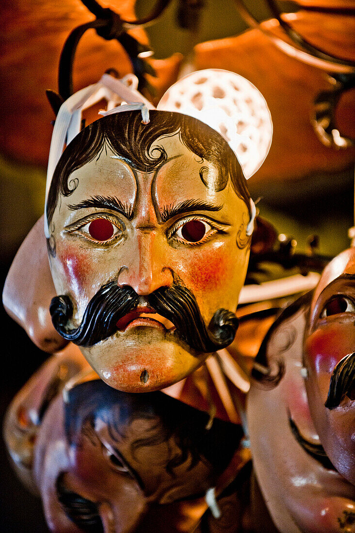 Masks of the Schellenruehrer hanging from a lamp, Mittenwald, Bavaria, Germany, Europe