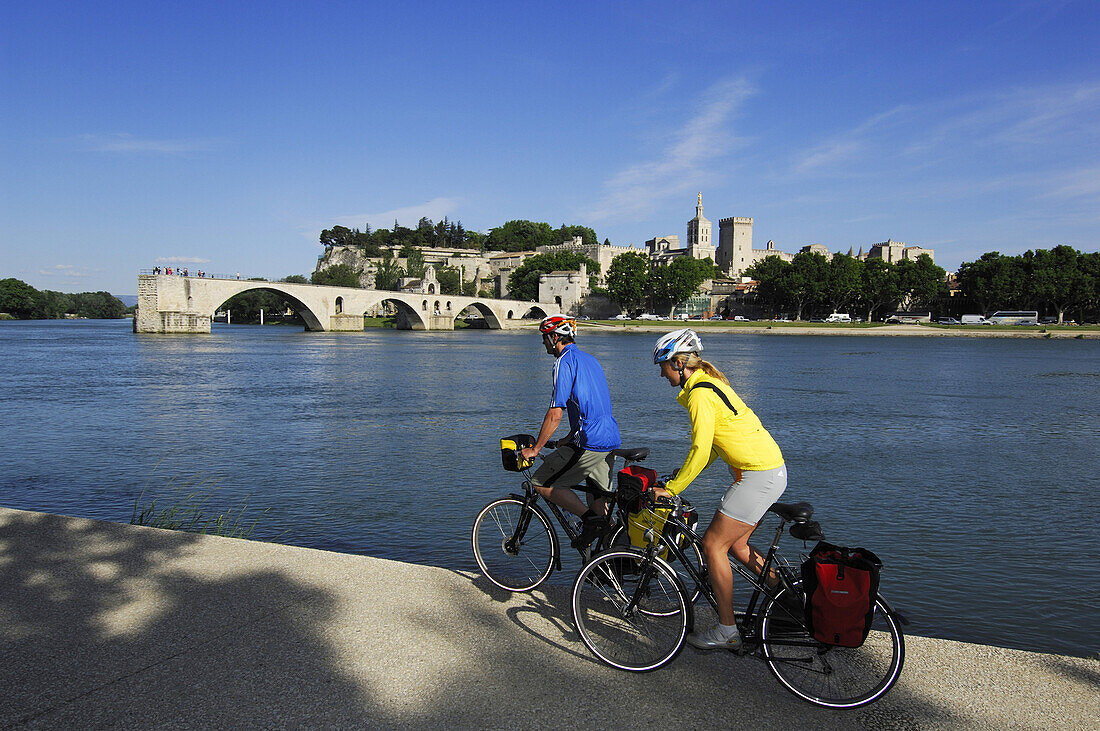 Cyclists in front of Saint Benezet bridge and the papal palace in Avignon, Provence, France