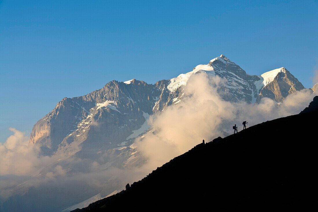 Two mountain hikers ascending, mount Jungfrau in backgound, Lauterbrunnen Valley, Canton of Bern, Switzerland