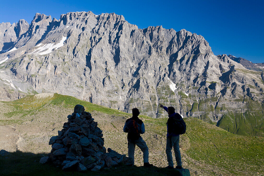 Two hikers watching rock face, Tschingelgrat, Lauterbrunnen Valley, Canton of Bern, Switzerland