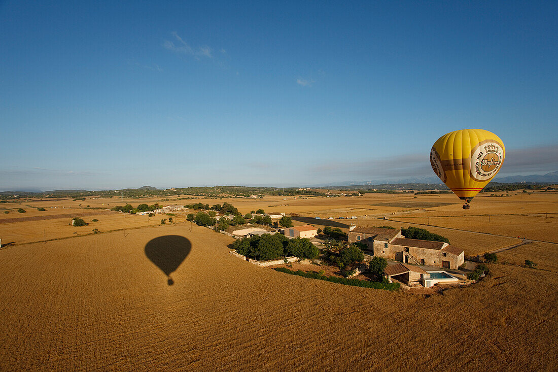 Hot air balloon flying over fields and a farm, plain Es Pla, Mallorca, Balearic Islands, Spain, Europe