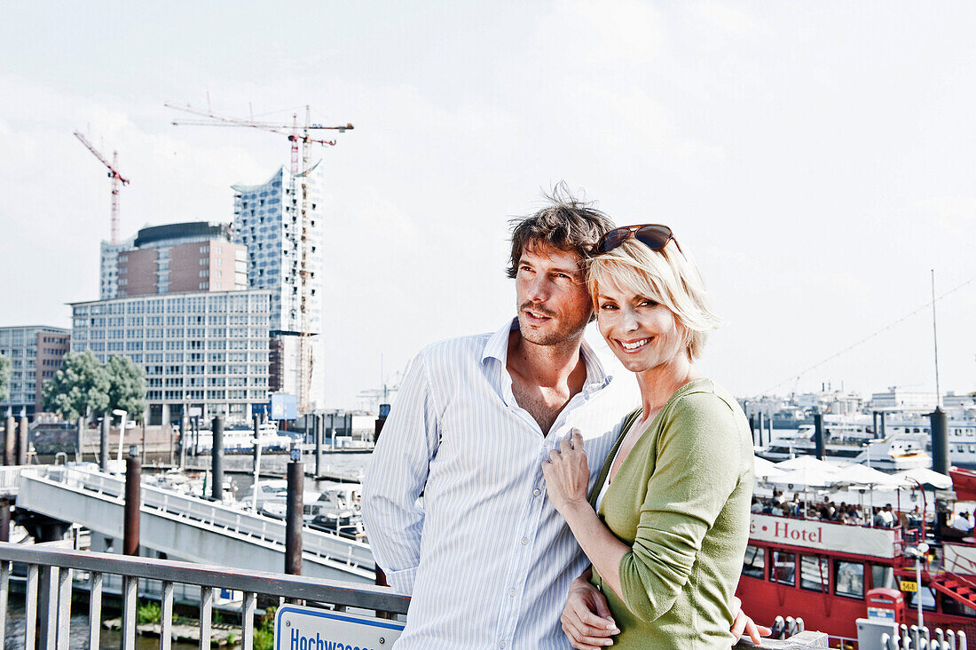 Couple embracing, Elbe Philharmonic Hall construction site in background, HafenCity, Hamburg, Germany