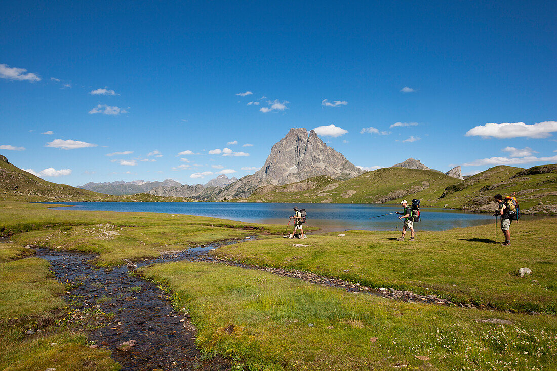 Hikers near lake Lac Gentau, Pic du Midi d'Ossau in background, Ossau Valley, French Pyrenees, Pyrenees-Atlantiques, Aquitaine, France