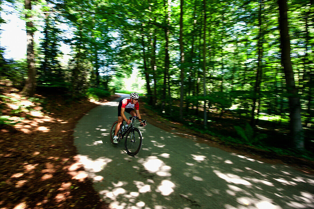 Man road cycling in forest, Bergisches Land, North Rhine-Westphalia, Germany