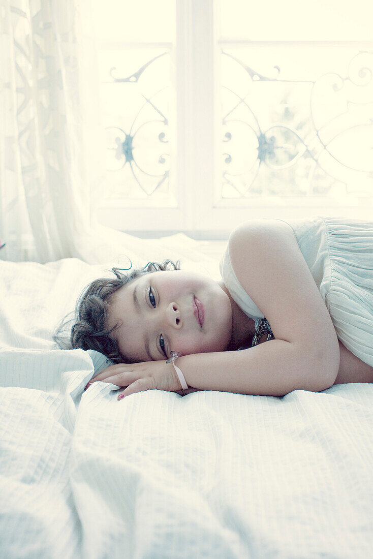 Smiling little girl lying on bed