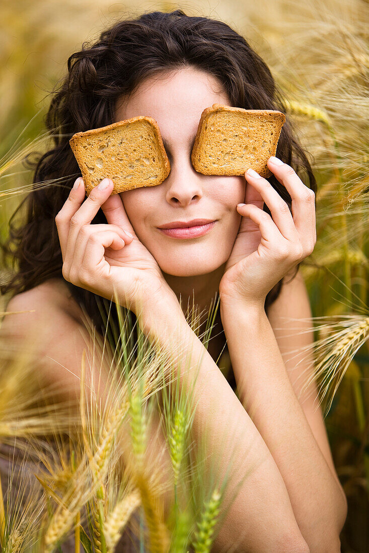 Young woman covering eyes with rusks