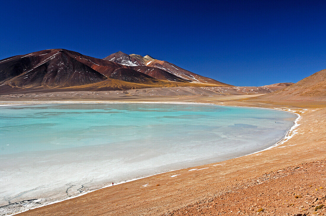 Chile, San Pedro de Atacama, Laguna Tuyajto, colored mountain in the back, person near the lake