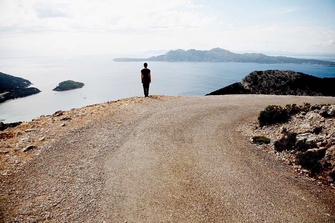 Woman Standing at Edge of Cliff Facing Mediterranean Sea, Mallorca, Spain