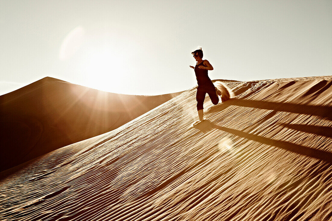 Woman Running Down Desert Sand Dune, California, USA