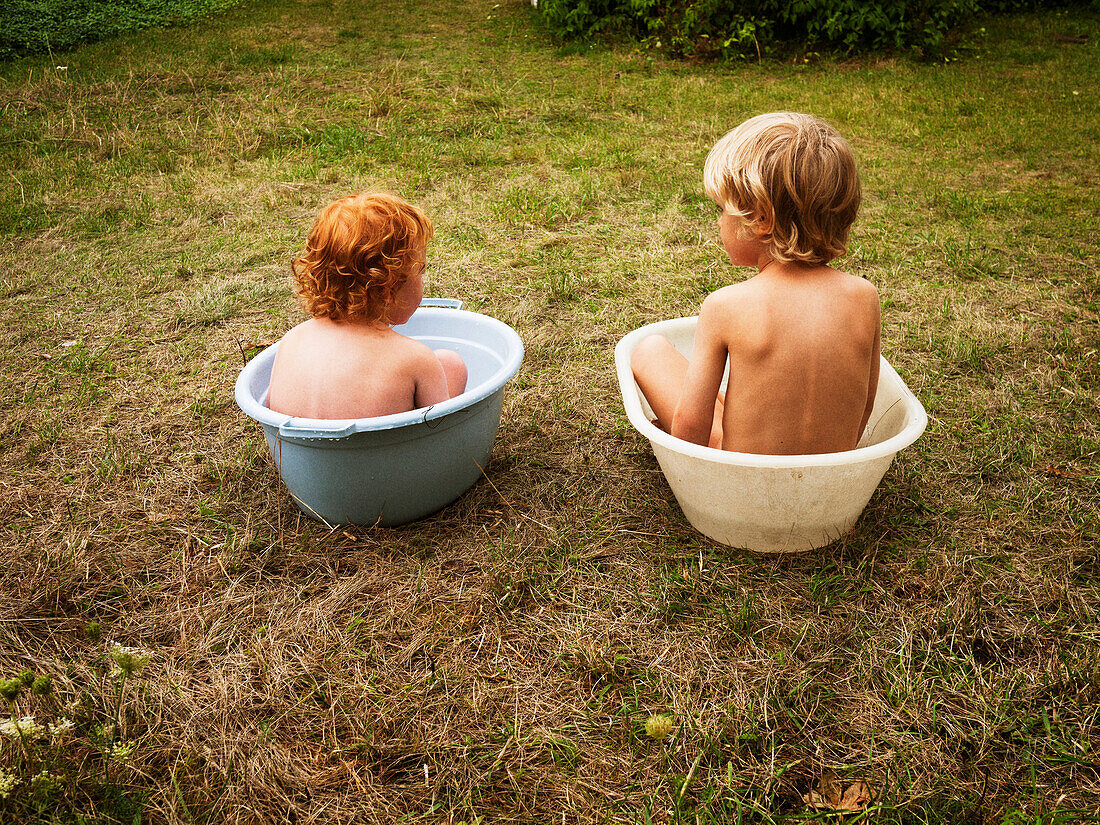 Two Young Children Sitting in Plastic Tubs