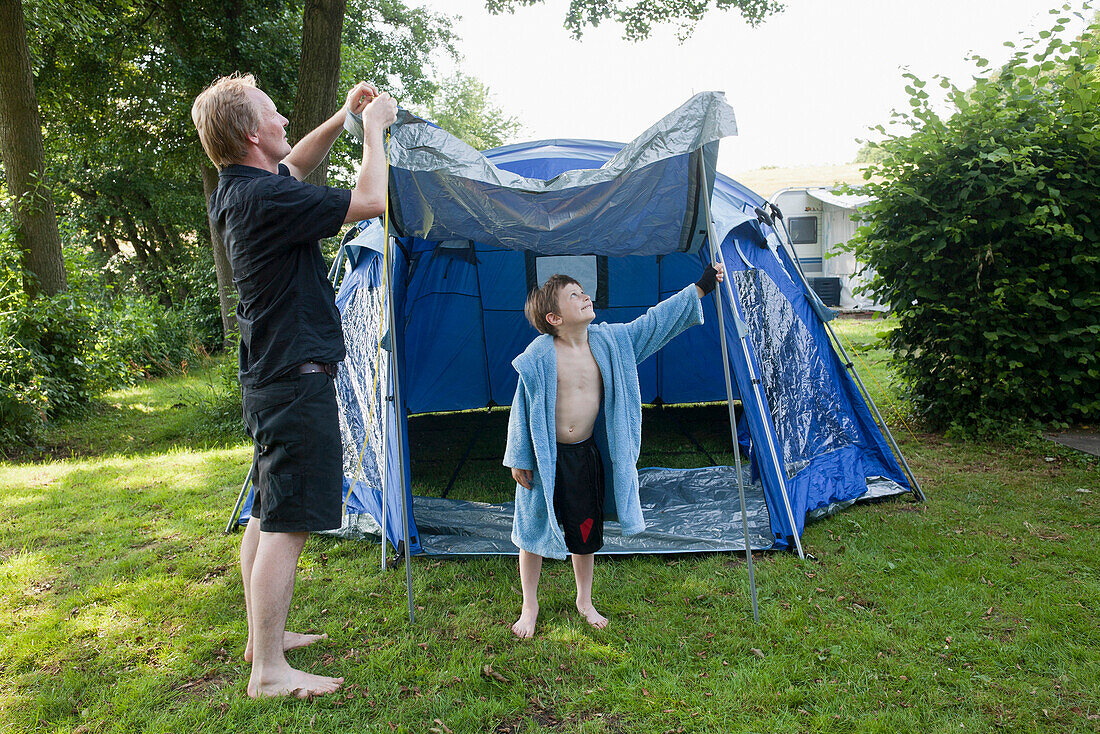 Father and son putting up a tent, campground, Lankau, Schleswig-Holstein, Germany
