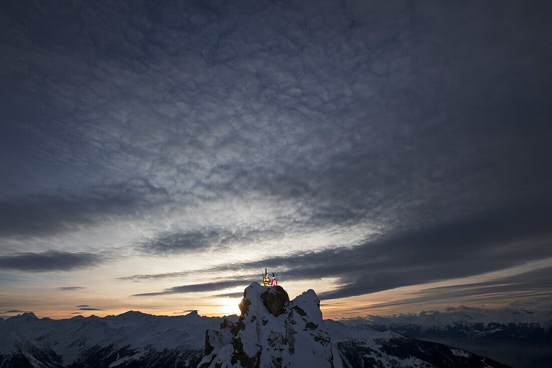 Two skiers standing on a mountain top in twilight, Chandolin, Anniviers, Valais, Switzerland